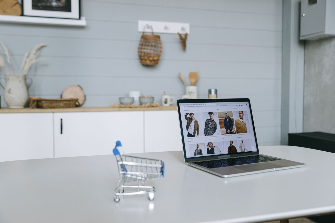 Crafting Captivating Headlines: Your awesome post title goes here A laptop displaying an online shopping portal sits on a minimal desk with a miniature shopping cart in focus.