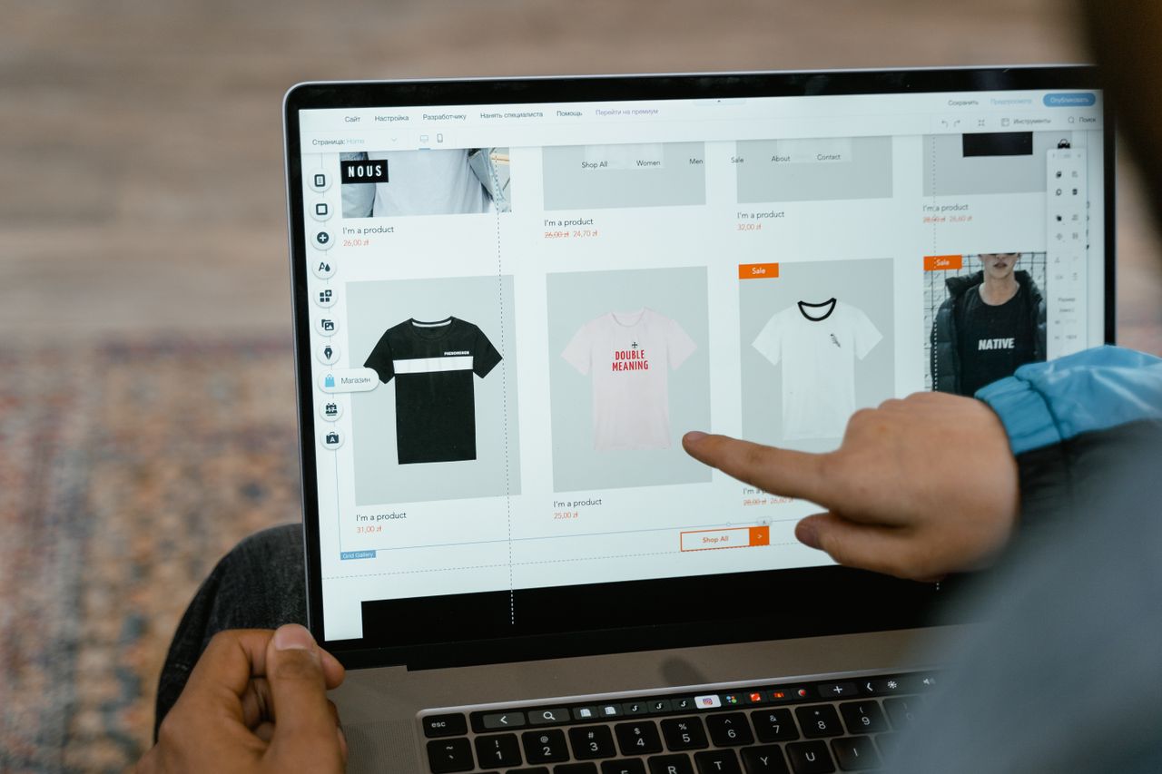 Mastering the First Impression: Your intriguing post title goes here A person points to t-shirt options in an online store on a laptop screen.